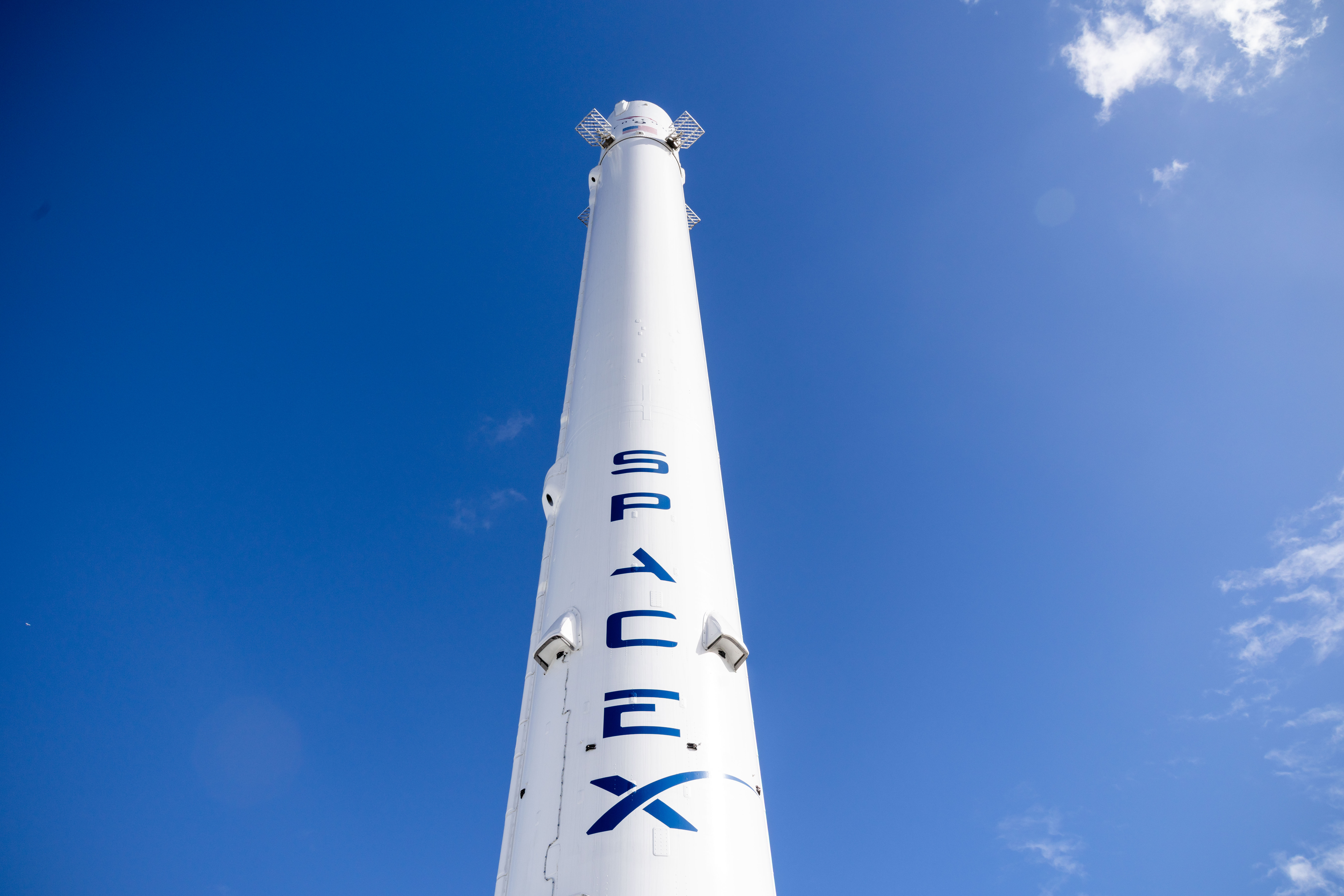Illustration of SpaceX rocket launching with superimposed logos of Tesla and X.