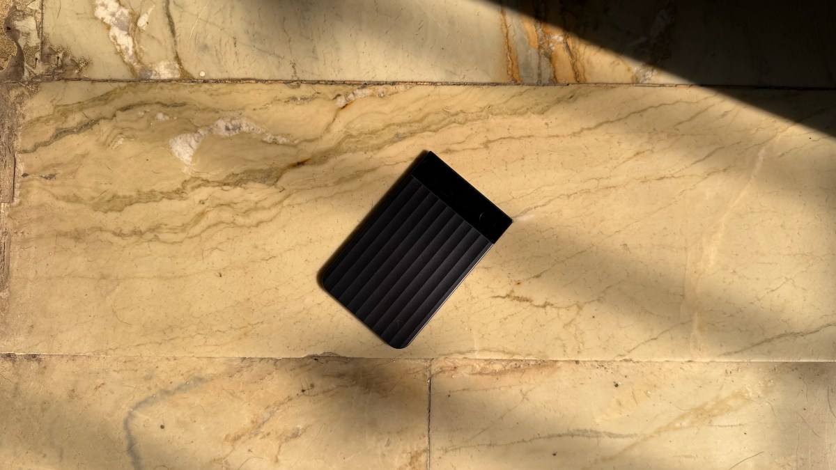 Assortment of credit-card sized and wearable AI notetaking devices on a wooden desk