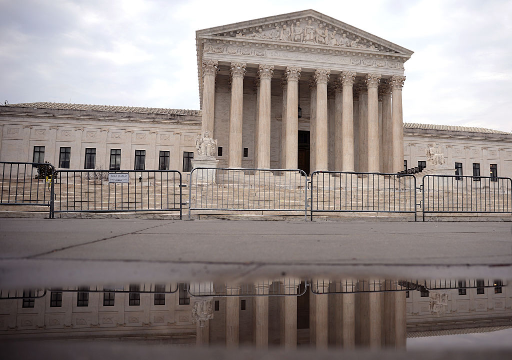 U.S. Supreme Court facade with stack of opinion documents in foreground
