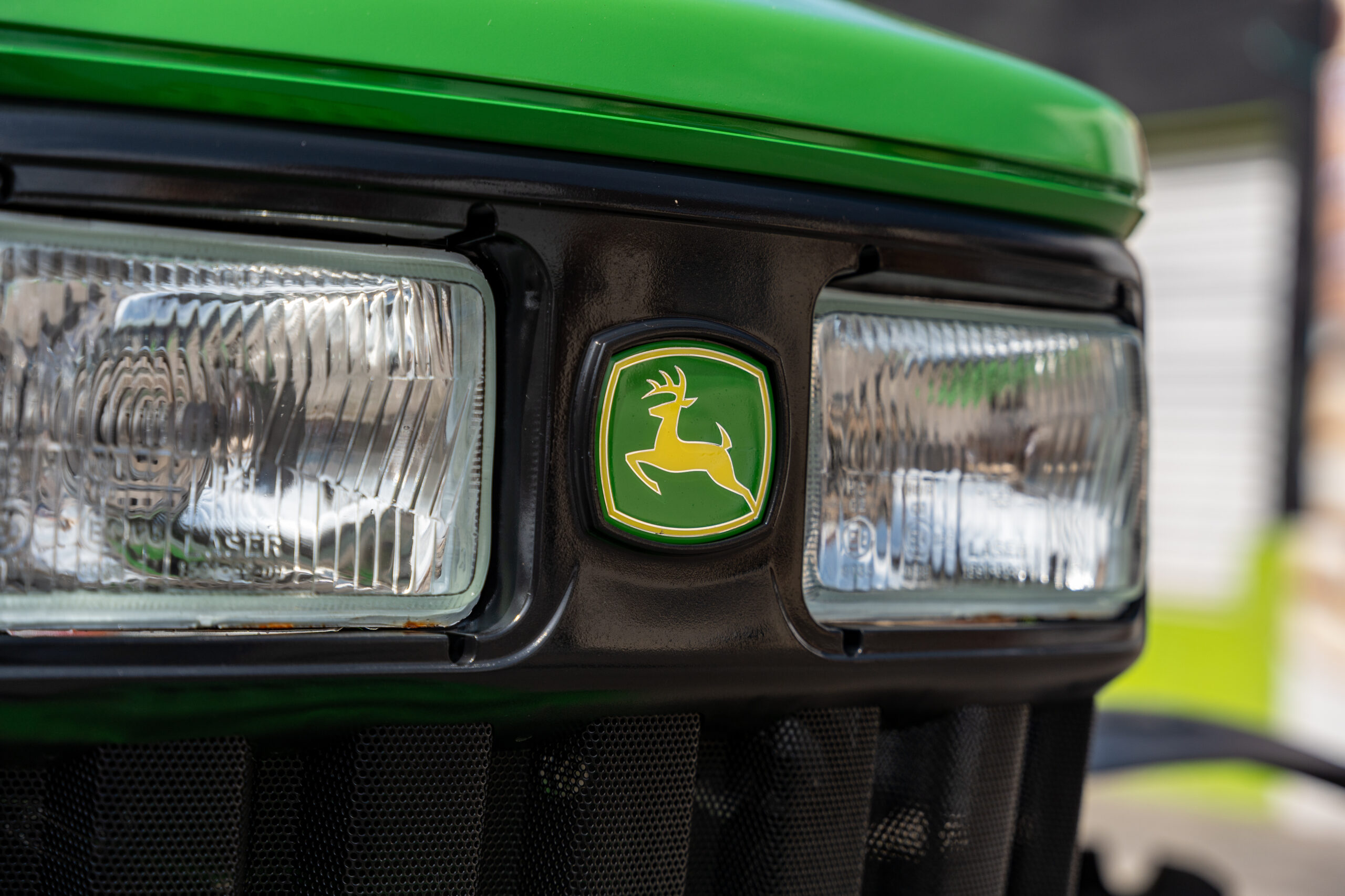 John Deere tractor being repaired by farmer in field with open hood and tools