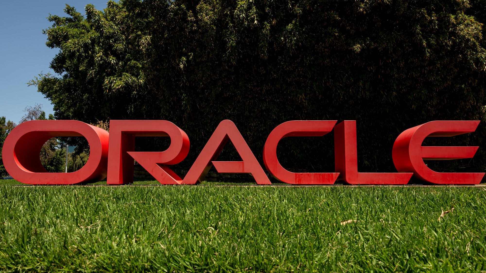 Oracle logo cracked open revealing glowing AI circuits and falling employee silhouettes