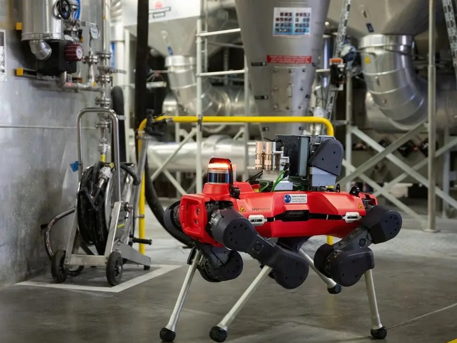 Four-legged ANYbotics robot inspecting machinery in a steamy industrial plant