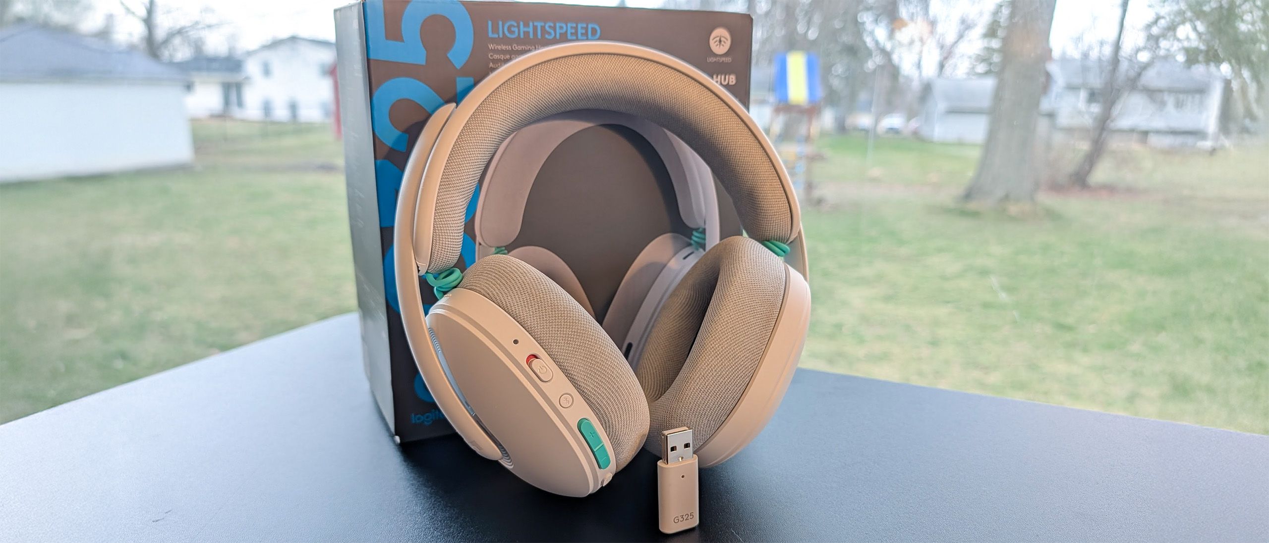 Logitech G325 Lightspeed wireless gaming headset in white with grey cushions and teal accents on a desk