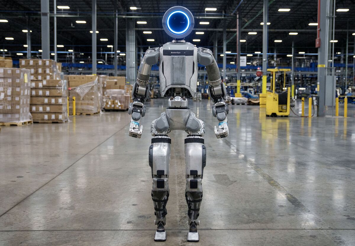 Atlas humanoid robot lifting car parts in futuristic Kia factory