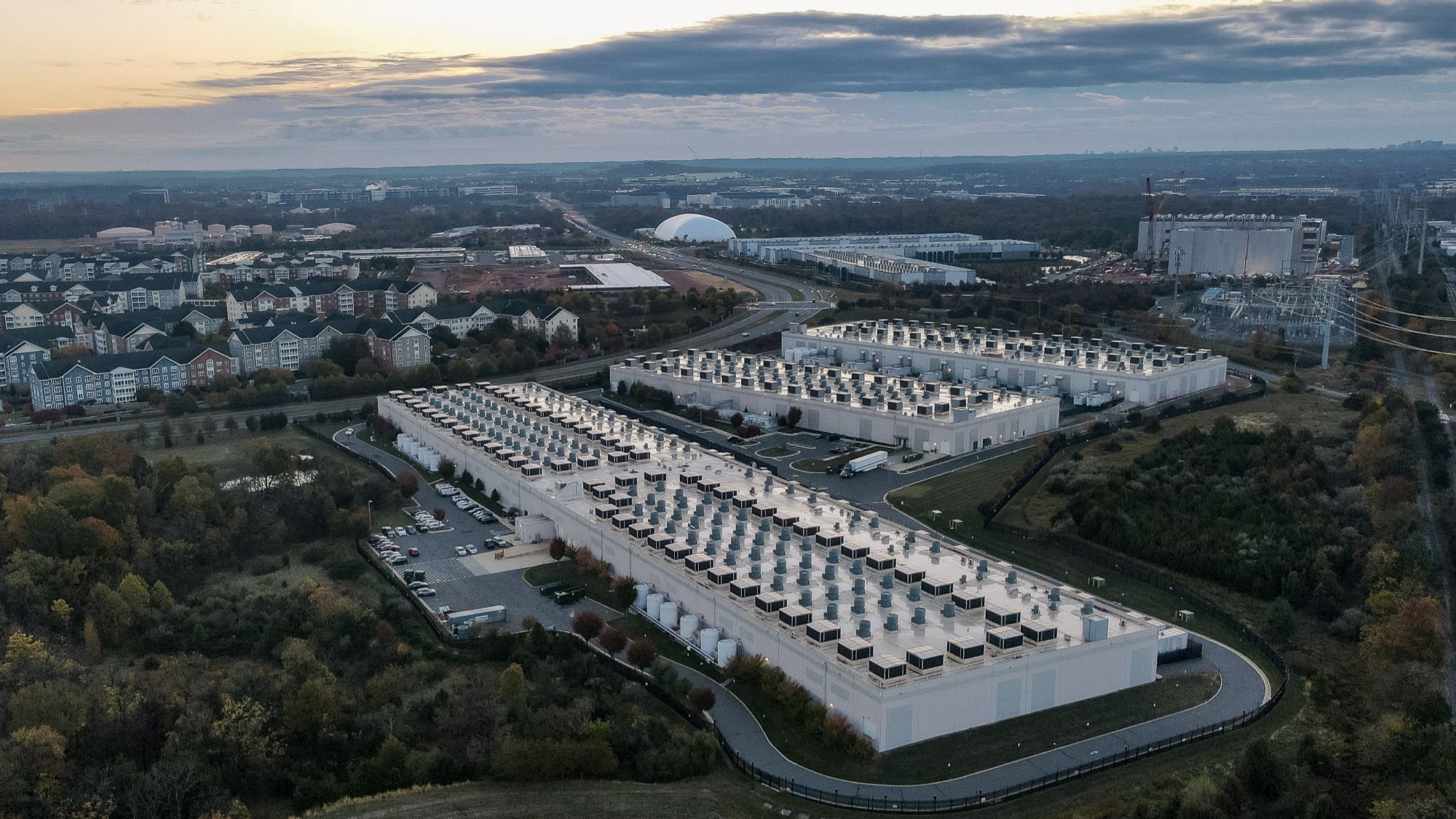 Artist's rendition of a sprawling data center campus with multiple buildings under a vast sky.