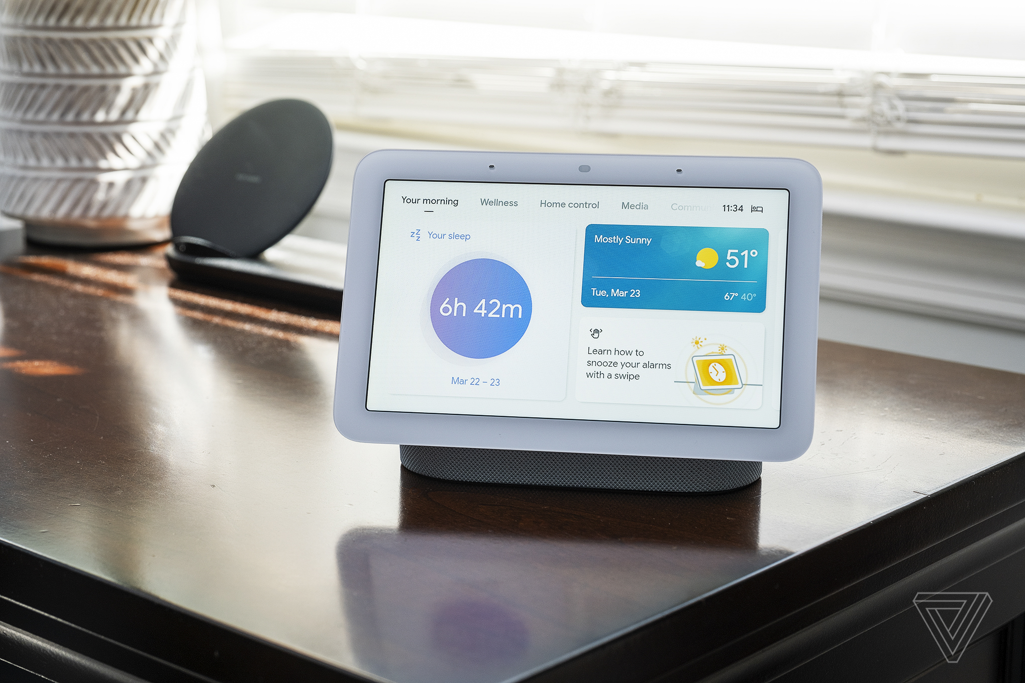 A person speaking to a Google Nest Hub device with the Gemini AI interface visible on screen.