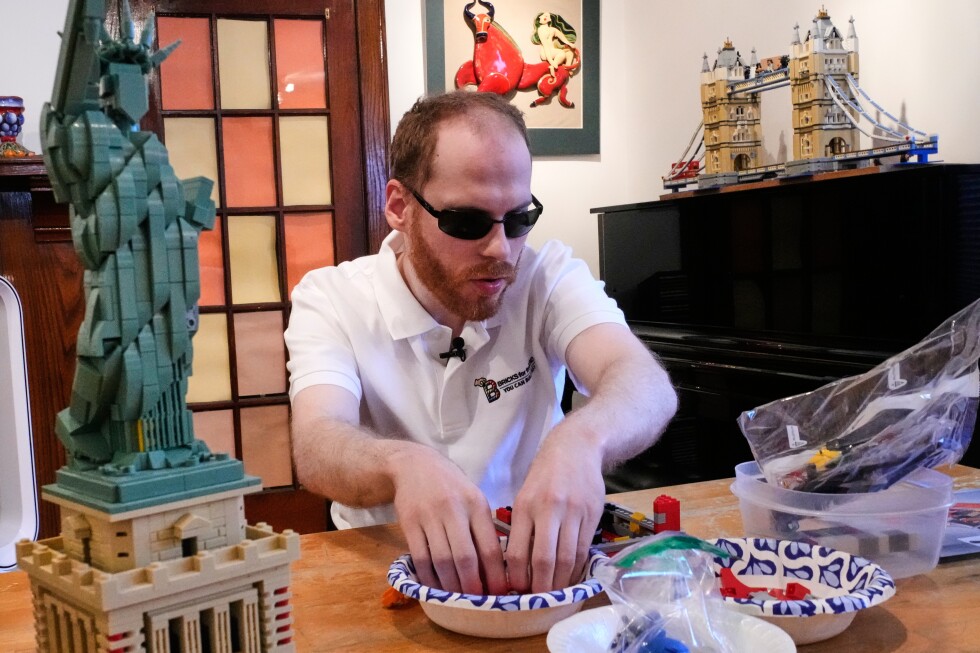 Matthew Shifrin, blind Lego enthusiast, surrounded by his completed sets including Apollo rocket and Statue of Liberty